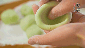 將均分的艾草面團(tuán)搓成圓，挖一個窩，放入餡心，再搓成圓。