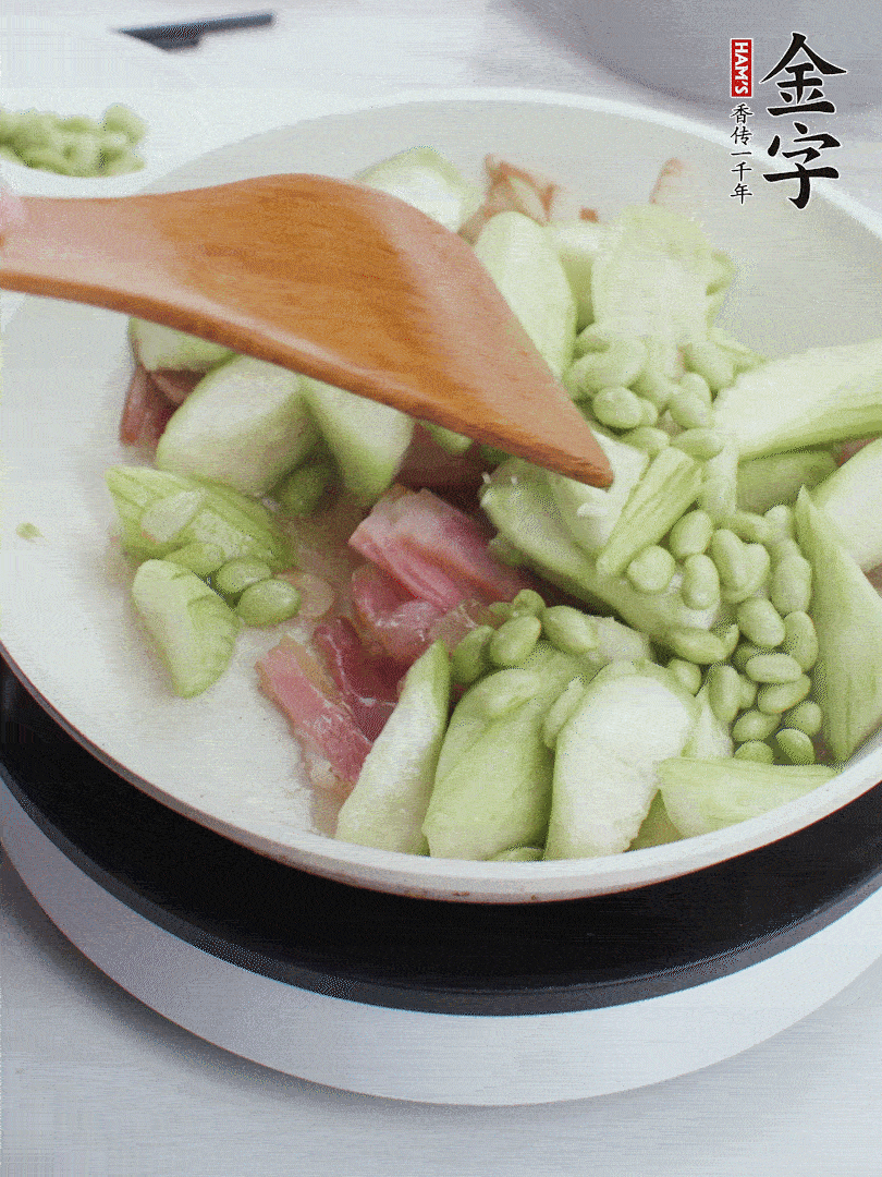 依次下絲瓜、青豆翻炒，炒至絲瓜打蔫縮小。