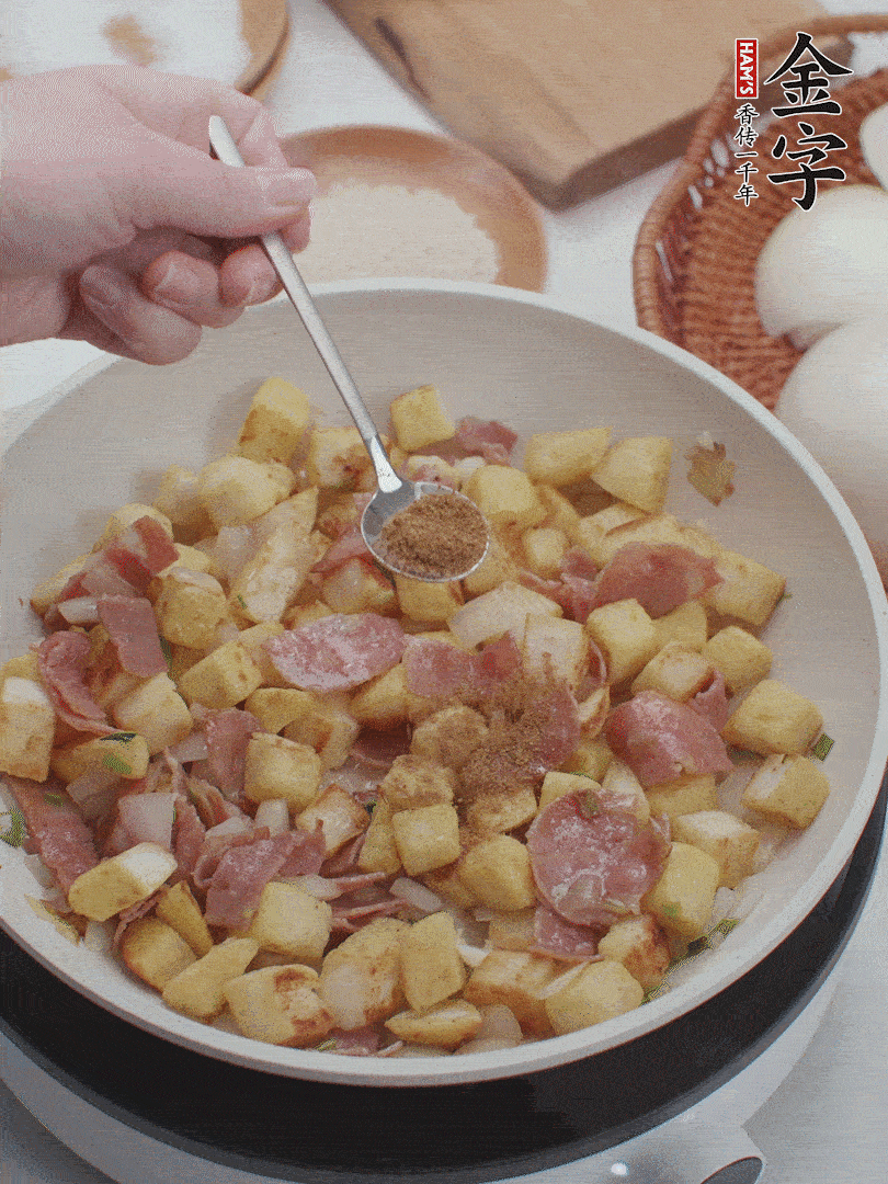 起鍋少油，煸香洋蔥丁、蔥白，加入金字培根火腿翻炒幾下，再加入饅頭丁、1小勺孜然粉、少許鹽翻炒均勻并鋪平。